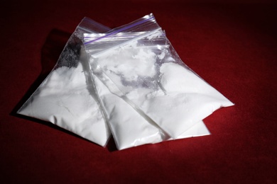 Photo of Cocaine in plastic bags on color background