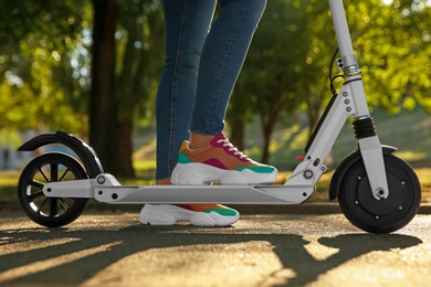 Photo of Woman riding electric kick scooter outdoors, closeup