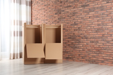 Photo of Empty cardboard wardrobe boxes against brick wall. Space for text
