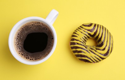 Photo of Tasty donut and cup of coffee on yellow background, flat lay