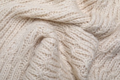 Photo of Beige knitted scarf as background, top view