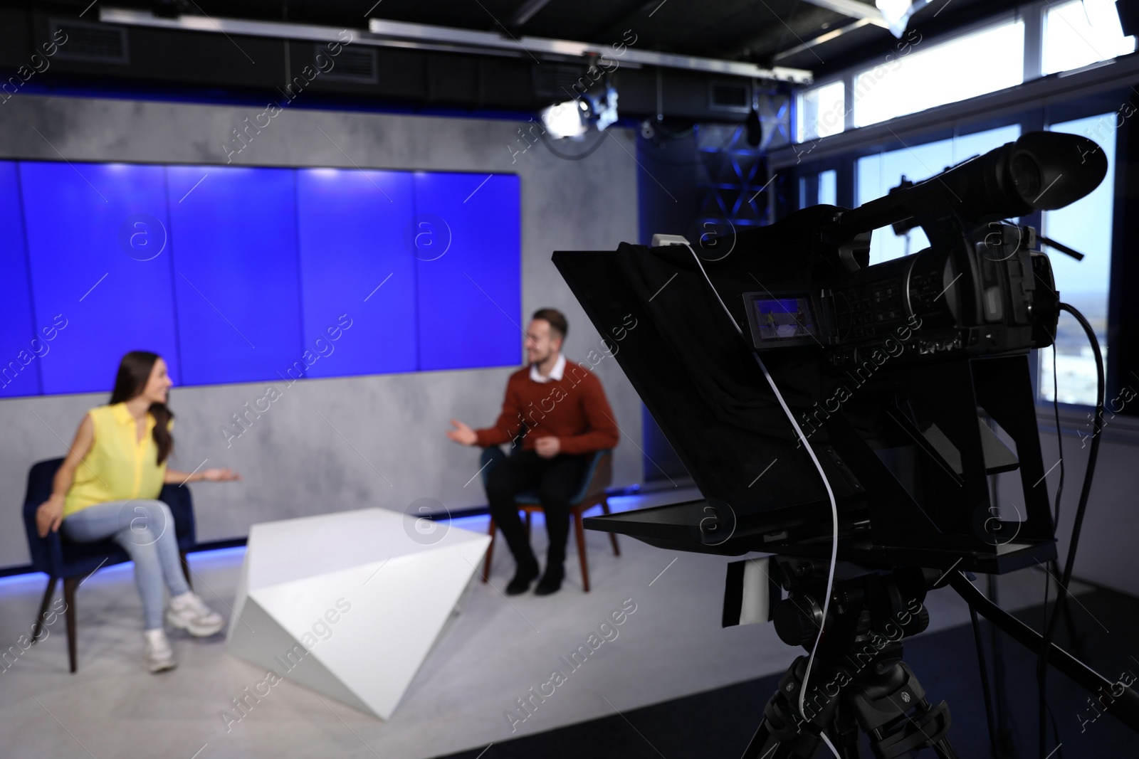 Photo of Presenters working in studio, focus on video camera