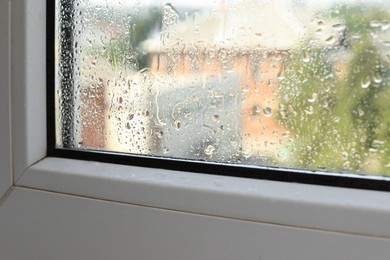 Photo of Wet window on rainy day, closeup. View from inside