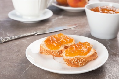 Photo of Plate with bread and tasty peach jam on table
