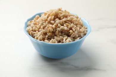 Photo of Delicious pearl barley in bowl on white marble table, closeup