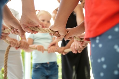 Photo of Little children holding rope, focus on hands. Unity concept