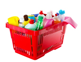 Photo of Shopping basket with different detergents and rag on white background