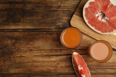 Photo of Glasses of pink pomelo juice and fruit on wooden table, flat lay. Space for text