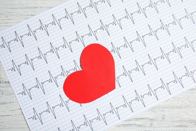 Photo of Red heart and cardiogram on wooden table, top view. Cardiology concept