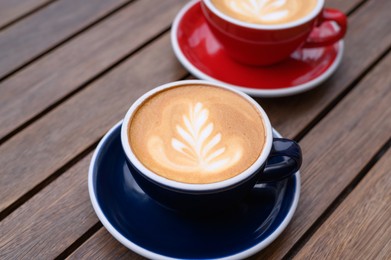 Photo of Cups of aromatic coffee on wooden table, closeup