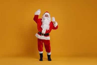 Photo of Merry Christmas. Santa Claus in headphones listening to music on orange background