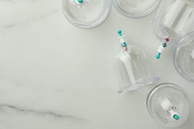 Photo of Plastic cups on white marble table, flat lay with space for text. Cupping therapy