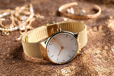 Photo of Luxury wrist watch on gold paillette background, closeup