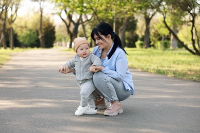 Photo of Mother supporting her baby while he learning to walk outdoors