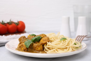 Photo of Delicious chicken, pasta with curry sauce and basil served on white table, closeup