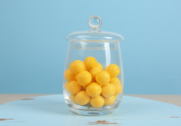 Photo of Tasty lemon drops in glass jar on wooden table