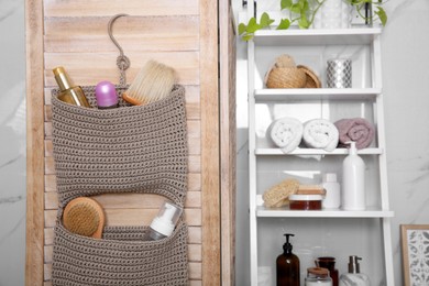 Photo of Knitted organizer hanging on wooden door in bathroom