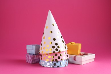 Photo of Party hats and gift boxes on pink background