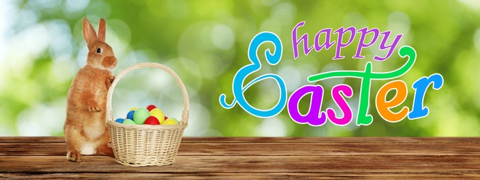 Image of Happy Easter. Adorable bunny and wicker basket with eggs on wooden table outdoors