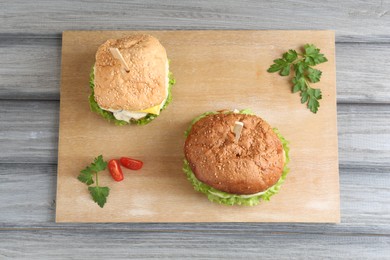 Photo of Delicious vegetarian burgers served on grey wooden table