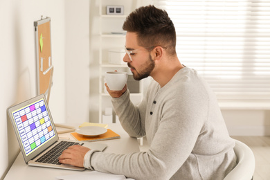 Photo of Young man using calendar app on laptop in office