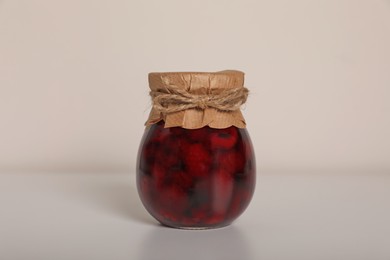 Photo of Tasty canned raspberry jam on white background