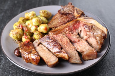 Photo of Delicious fried beef meat and vegetables on black table, closeup