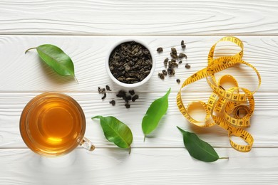 Photo of Flat lay composition with herbal diet tea and measuring tape on white wooden table. Weight loss concept