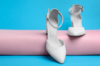 Photo of Stylish white female shoes on light blue background