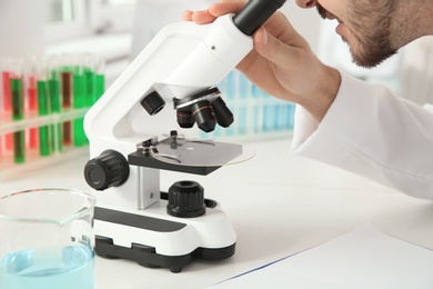 Photo of Medical student working with microscope in modern scientific laboratory, closeup