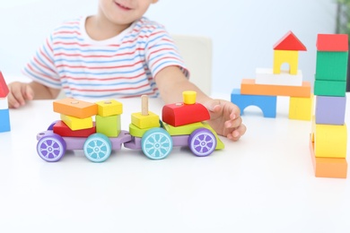 Photo of Little boy playing with toy at white table, closeup