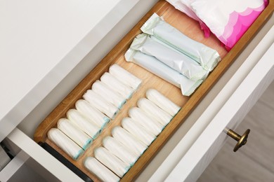 Photo of Storage of different feminine products in white drawer indoors