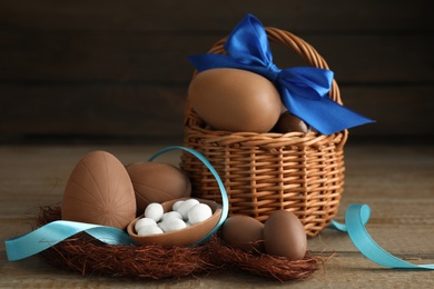 Photo of Delicious chocolate Easter eggs and ribbon on wooden table