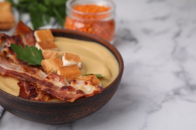 Photo of Delicious lentil soup with bacon and parsley in bowl on light marble table, closeup. Space for text