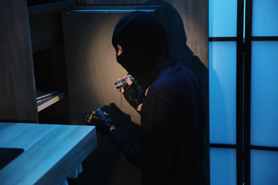 Photo of Thief taking gold bars out of steel safe indoors at night