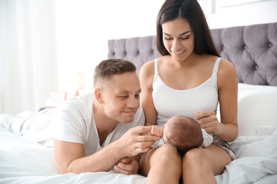 Photo of Happy couple with their newborn baby on bed