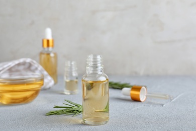 Photo of Glass bottle of essential oil and rosemary on table. Space for text