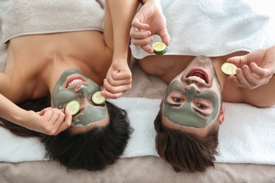 Photo of Happy couple enjoying facial treatment procedure in spa salon, above view