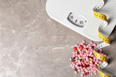 Photo of Weight loss pills with scales and measuring tape on gray background, flat lay. Space for text