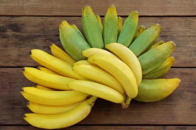 Bunches of tasty bananas on wooden table, flat lay