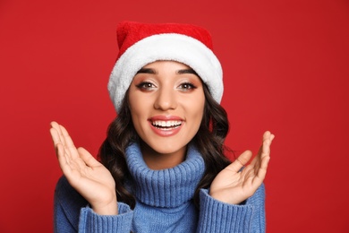 Beautiful woman in Santa hat on red background. Christmas party