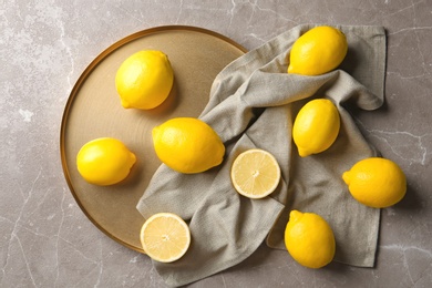Photo of Flat lay composition with lemons, fabric and golden plate on gray background