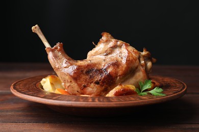 Photo of Tasty cooked rabbit meat with potatoes on wooden table, closeup