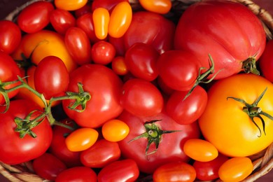 Photo of Wicker basket with fresh tomatoes on wooden table, top view