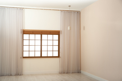 Photo of Window with beautiful curtains and open blinds in empty room