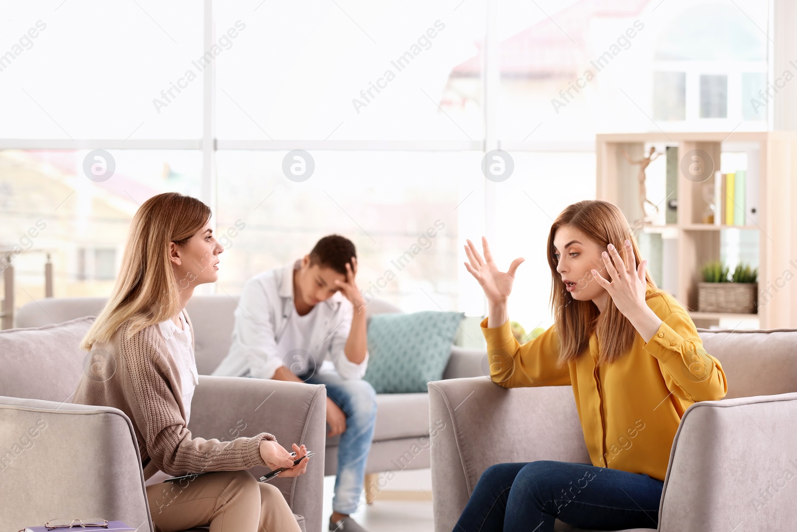 Photo of Young female psychologist working with teenage boy and his mother in office
