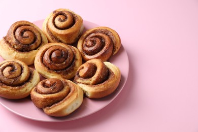 Photo of Many tasty cinnamon rolls on pink background, closeup. Space for text