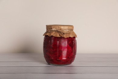 Photo of Jar with pickled beetroot on white wooden table