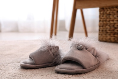 Photo of Pair of light grey slippers on floor in room