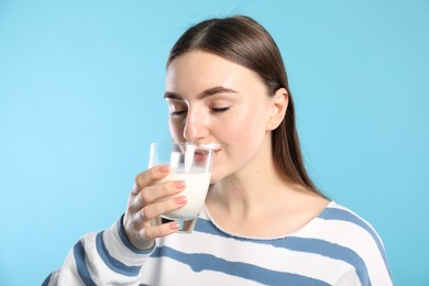 Photo of Milk mustache left after dairy product. Woman drinking milk on light blue background